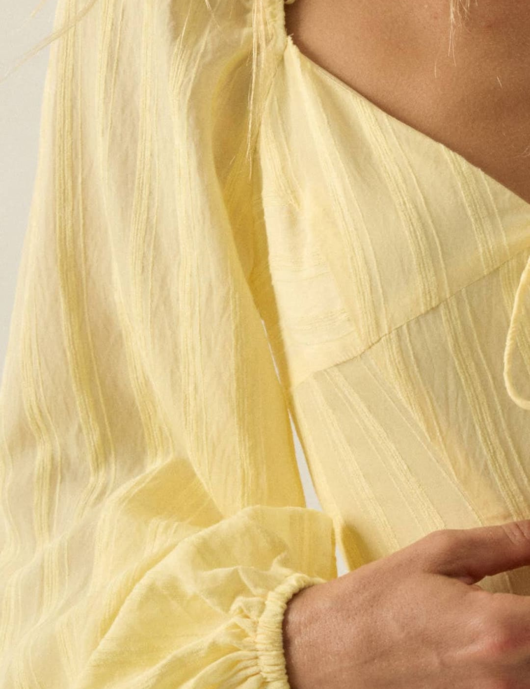 A delicate, pale yellow dress with a flowing, lightweight fabric and gathered sleeves.