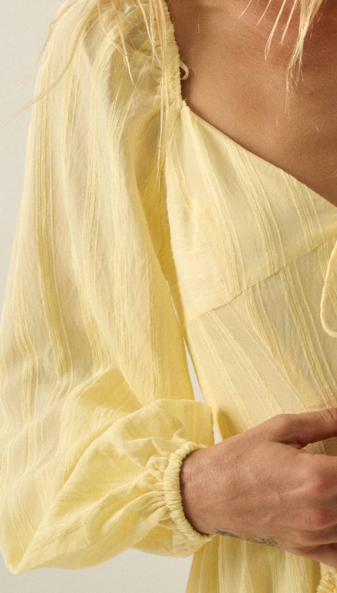 A delicate, pale yellow dress with a flowing, lightweight fabric and gathered sleeves.