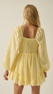 A pale yellow, lightweight dress with puffy long sleeves and a square neckline.
