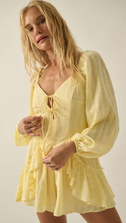 A soft yellow, lightweight dress with long puffy sleeves and a ruffled hem.