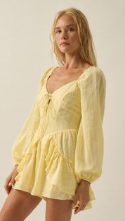 A soft yellow, lightweight fabric romper with long puffy sleeves and a ruffled hem.