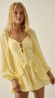 A soft yellow, long-sleeved romper with a lace-up front and ruffled hem.