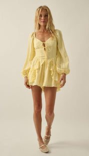 A soft yellow, long-sleeved mini dress with a ruffled hem and lace-up front.