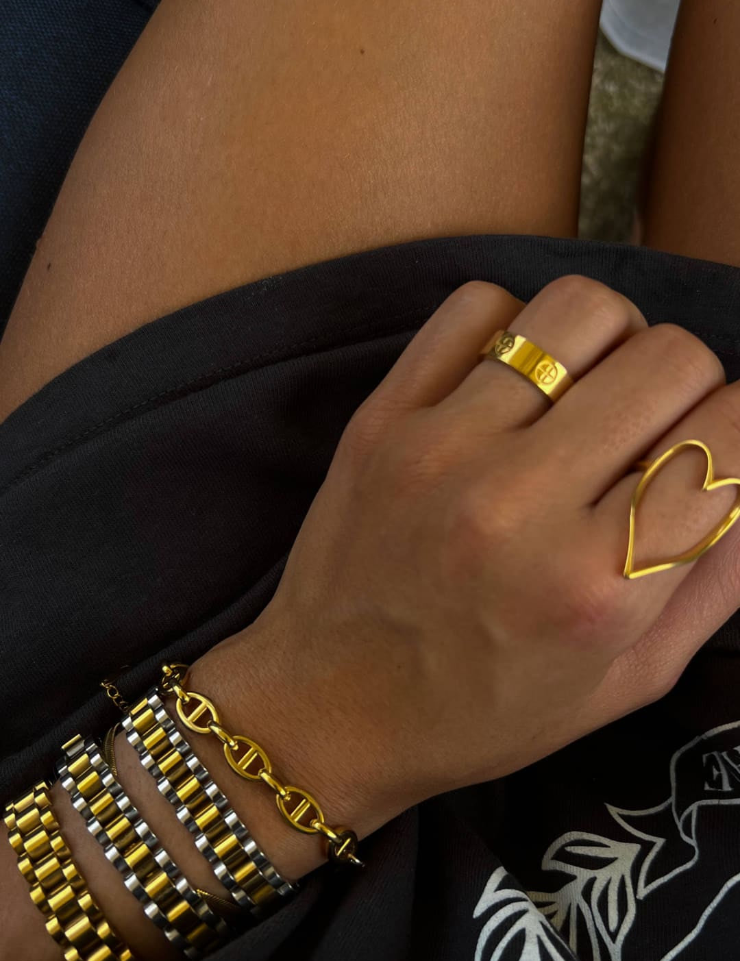 Gold heart-shaped ring with a sleek, open design worn on the index finger