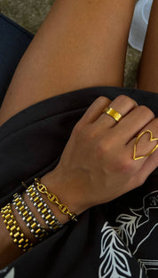 Gold heart-shaped ring with a sleek, open design worn on the index finger