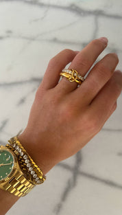 Gold-tone watch with a green dial and diamond accents on the bezel, paired with matching gold-toned bracelets featuring embedded diamonds.