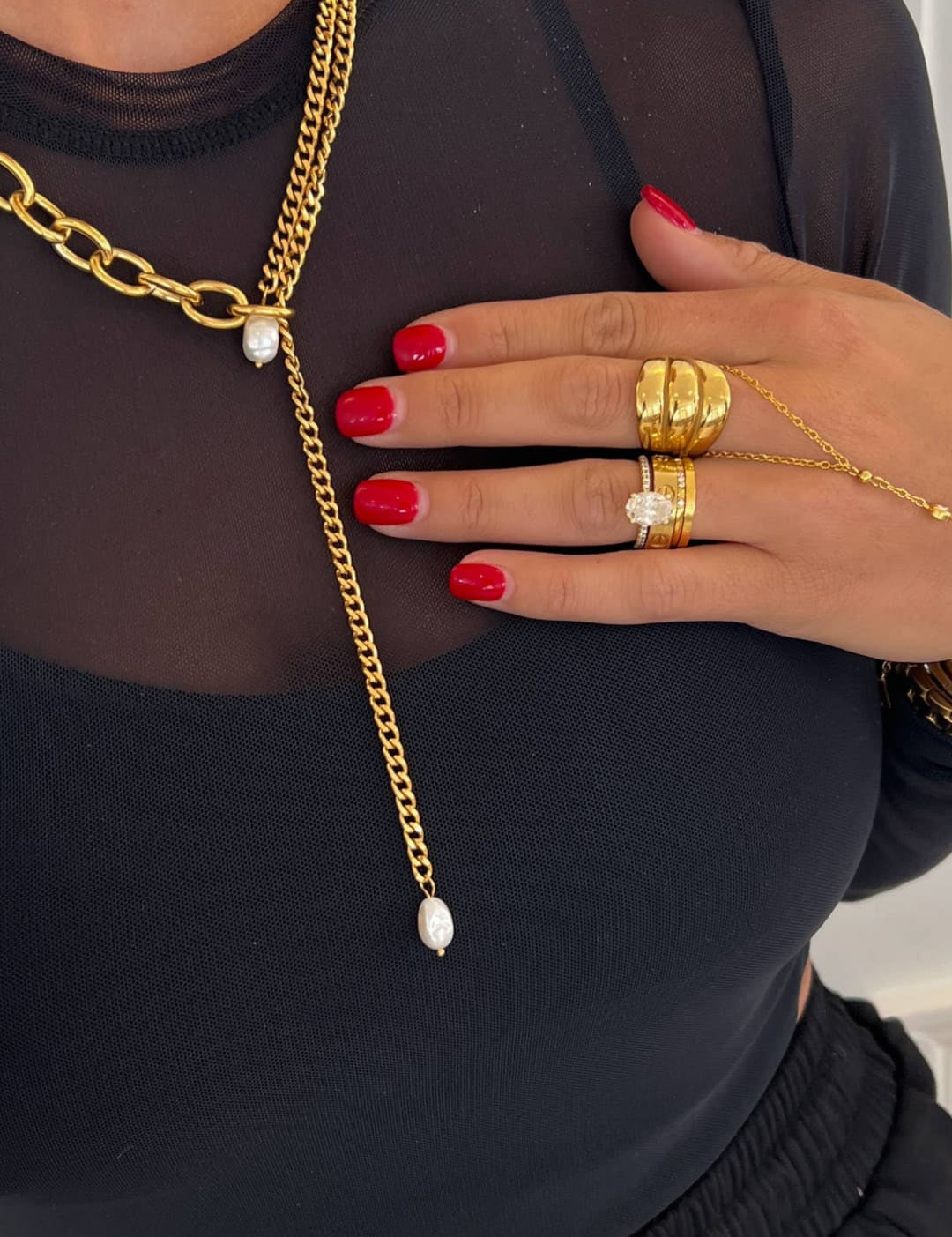 Gold chain necklace with a layered design featuring thick curb links and delicate fine chains, accented by two white pearls at the center.