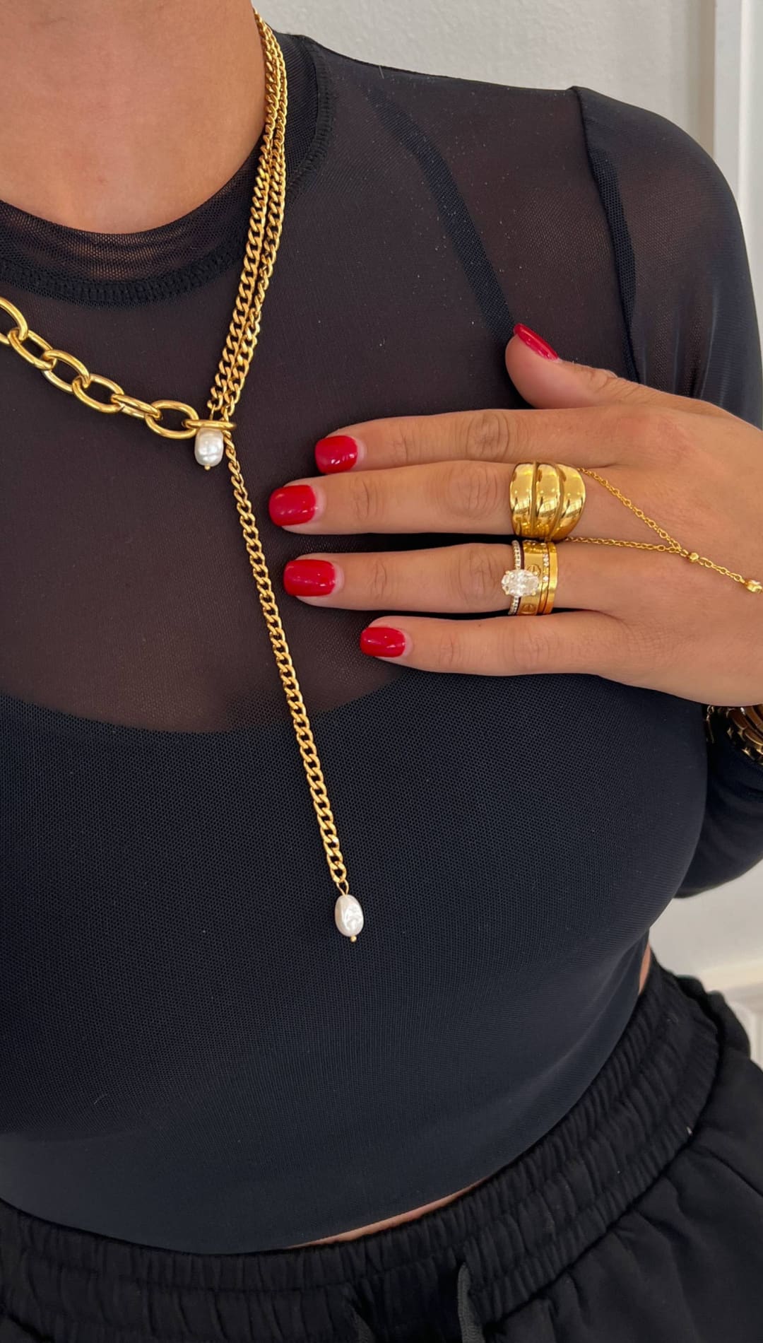 Gold chain necklace with a layered design featuring thick curb links and delicate fine chains, accented by two white pearls at the center.