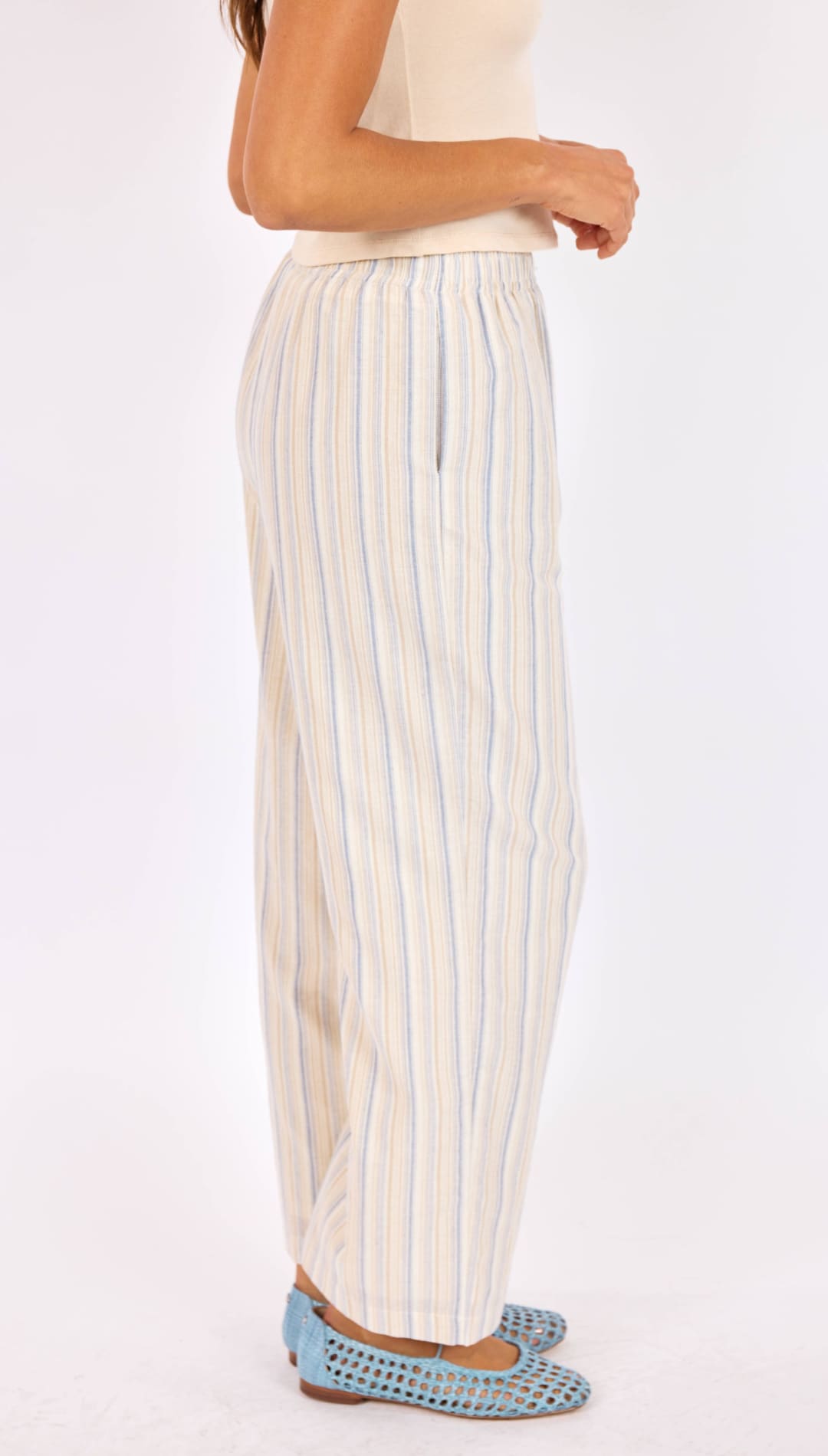Cream-colored wide-leg trousers with thin vertical stripes in light blue and white, made of a soft, flowing fabric.