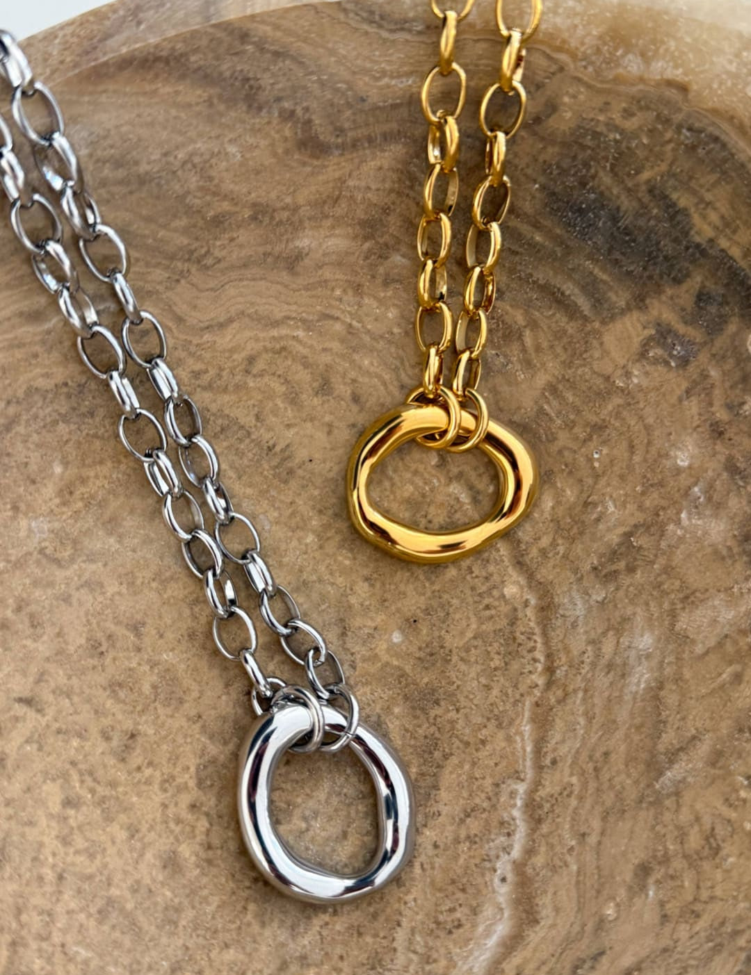 Silver and gold chain necklaces featuring oval ring pendants with a sleek, minimalist design.