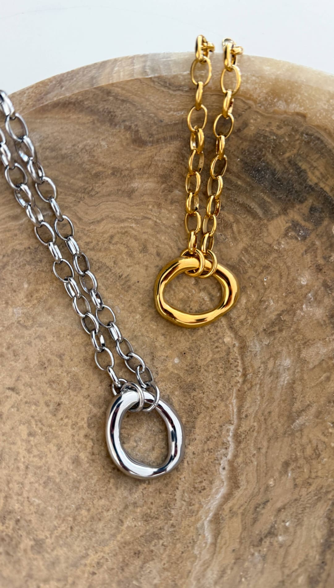 Silver and gold chain necklaces featuring oval ring pendants with a sleek, minimalist design.