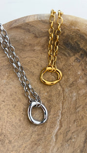 Silver and gold chain necklaces featuring oval ring pendants with a sleek, minimalist design.