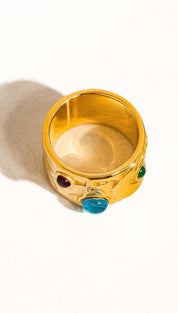 Gold-colored ring featuring a sculpted design with embedded red, green, and blue gemstones.