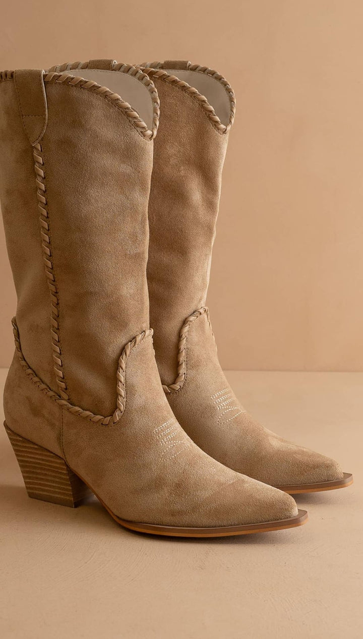 Beige suede cowboy boots with braided detailing and a stacked heel.