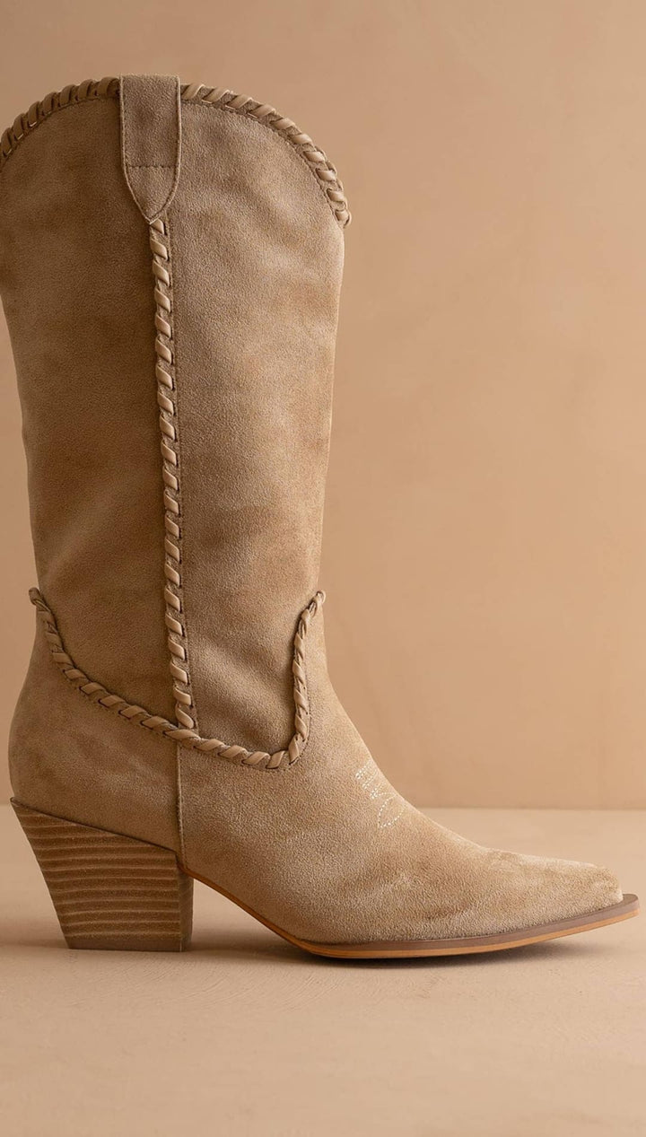 Beige suede cowboy boot with braided leather detailing and a stacked heel.