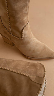 Tan suede cowboy boot with a pointed toe and braided stitching along the shaft.