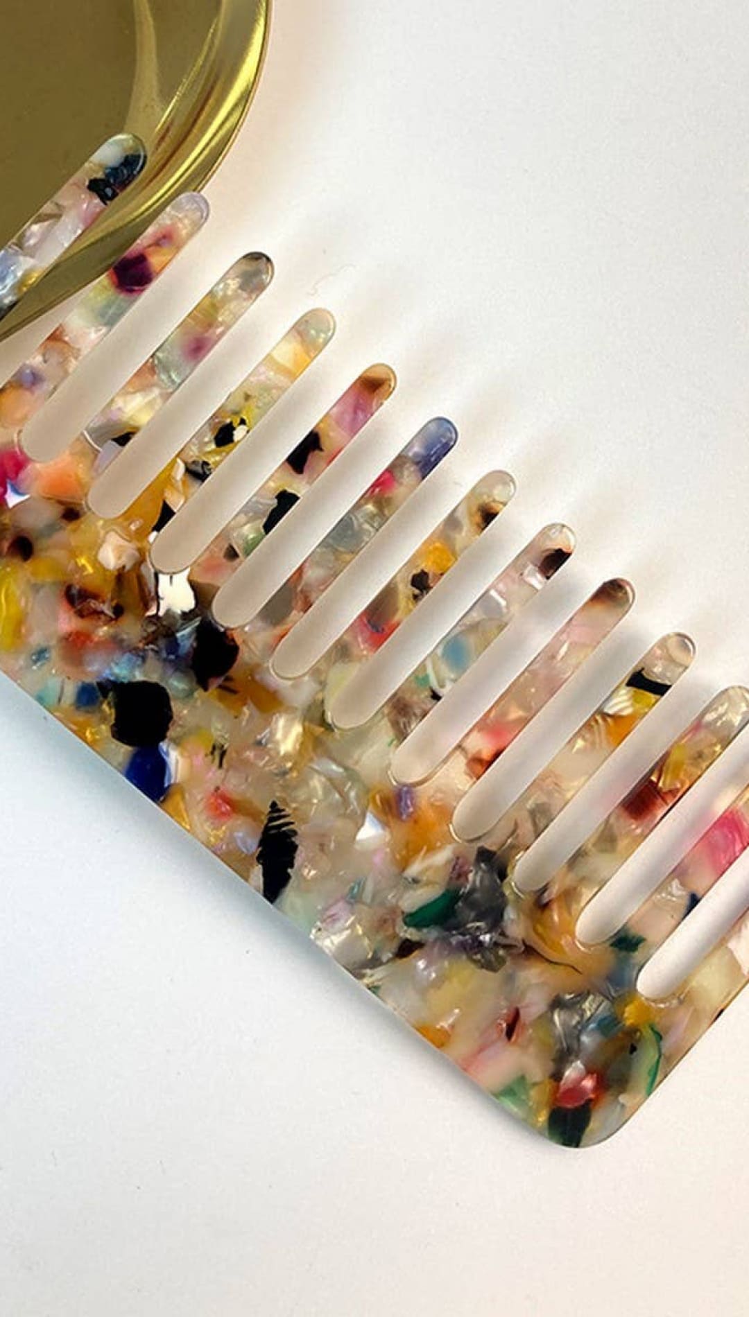 Floral print hair comb with clear plastic teeth and a colorful, translucent resin body.