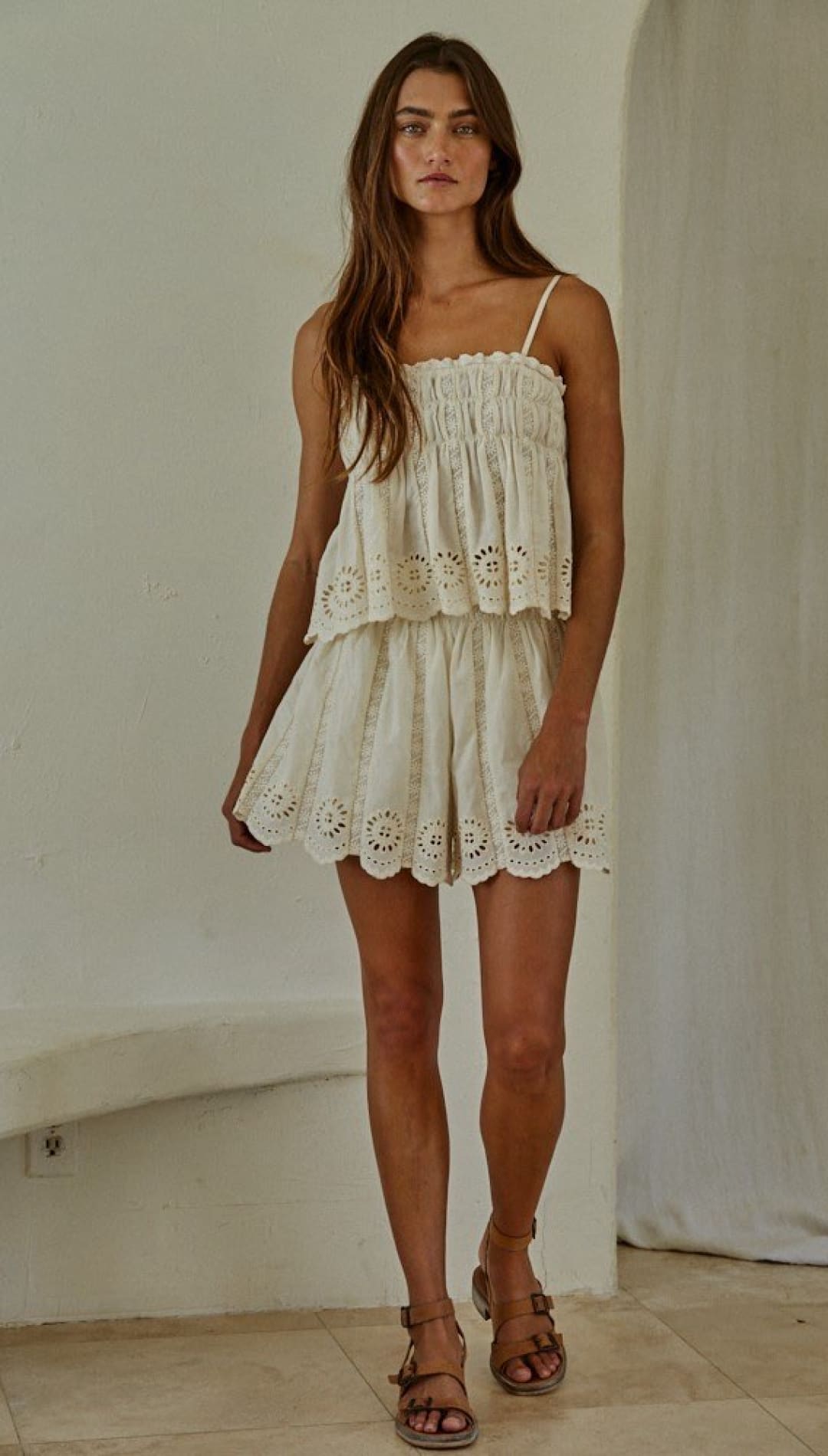 White eyelet lace romper with spaghetti straps and tiered ruffle design.