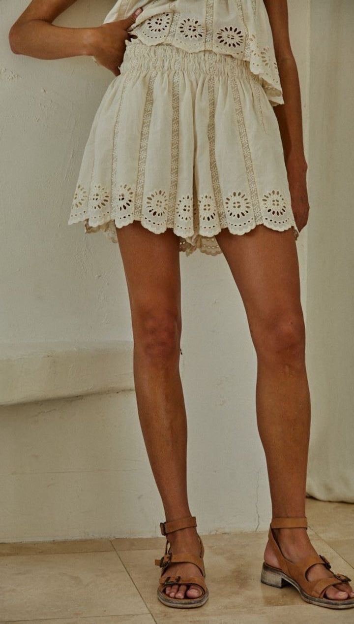 White eyelet lace mini skirt with scalloped hem detailing.