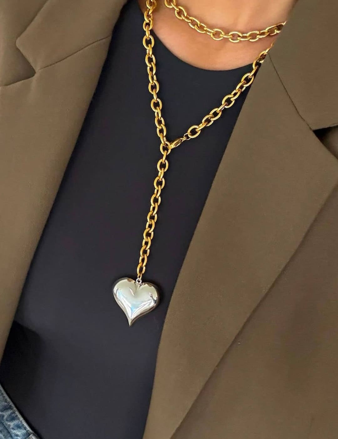 Gold chain necklace with a silver heart pendant.