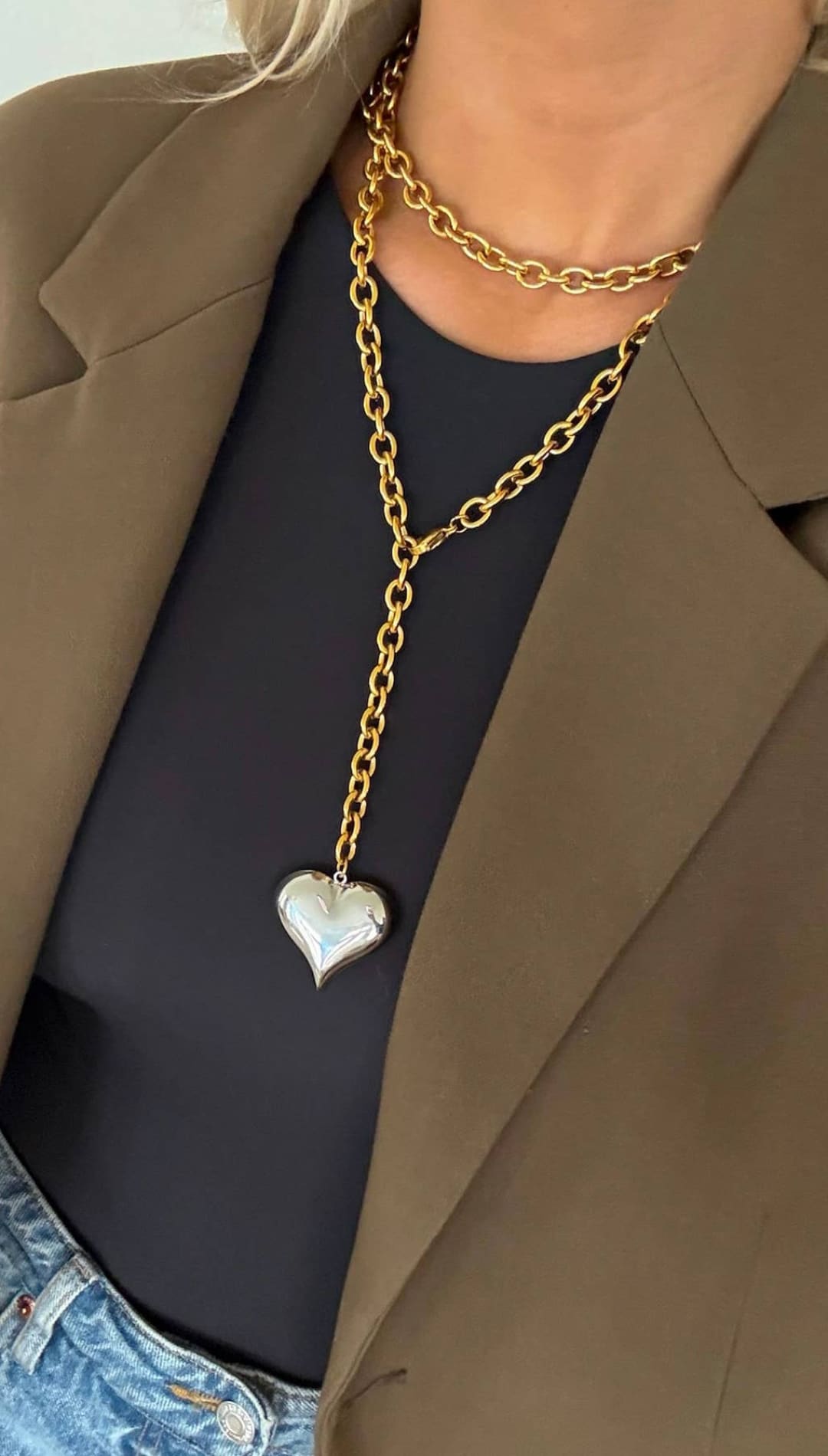 Gold chain necklace with a silver heart pendant.