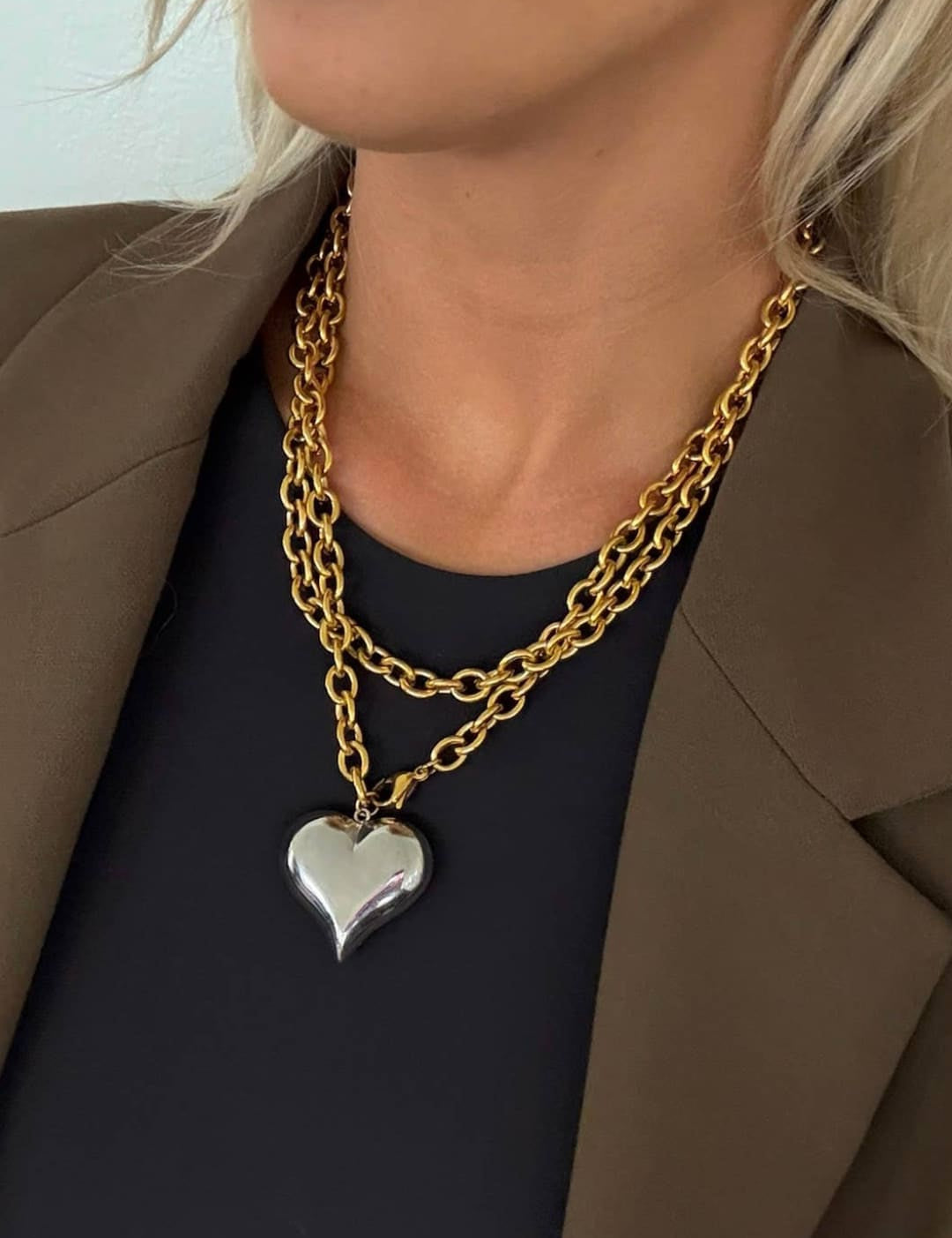 Gold chain necklace with a silver heart pendant.