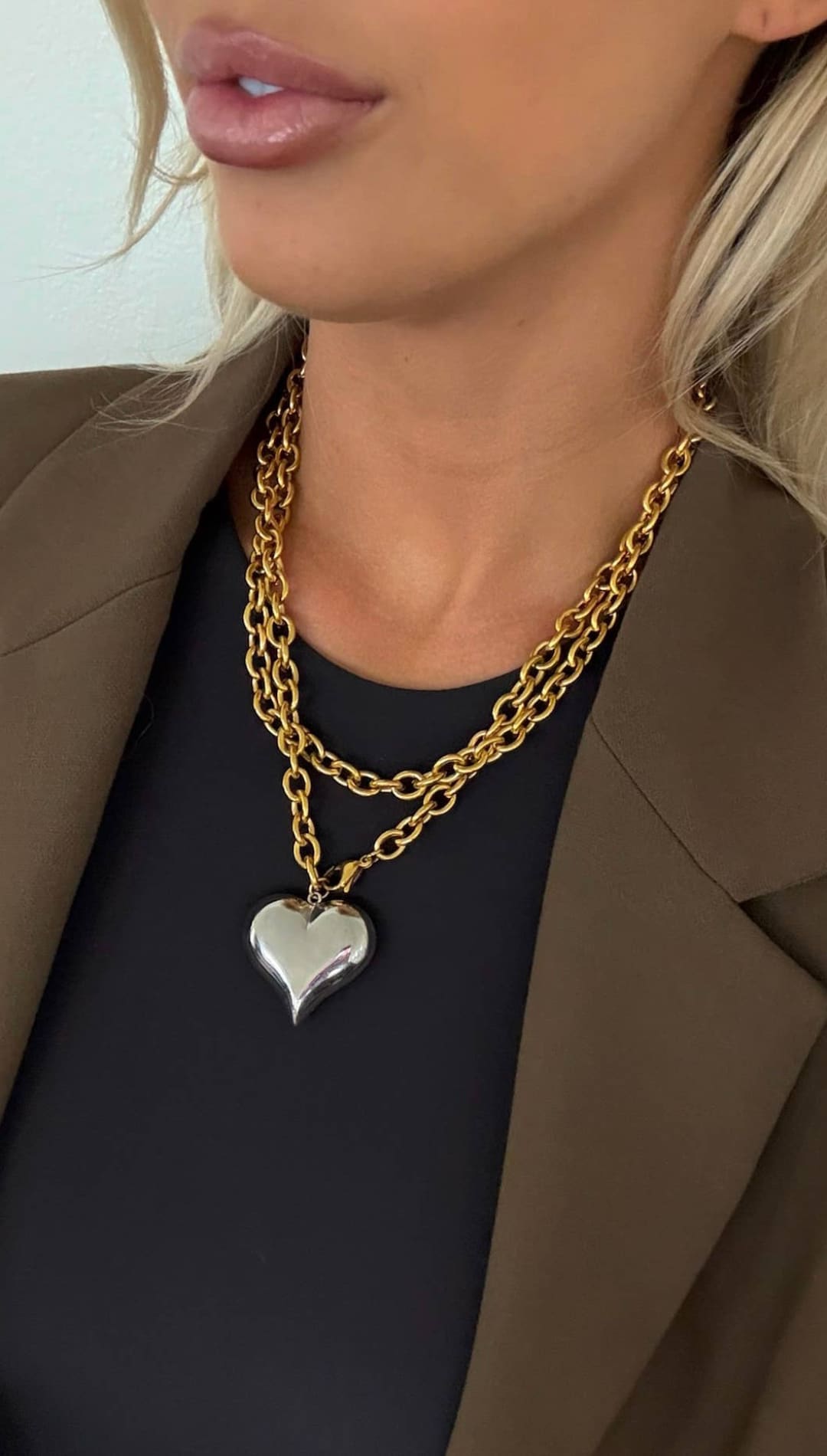 Gold chain necklace with a silver heart pendant.