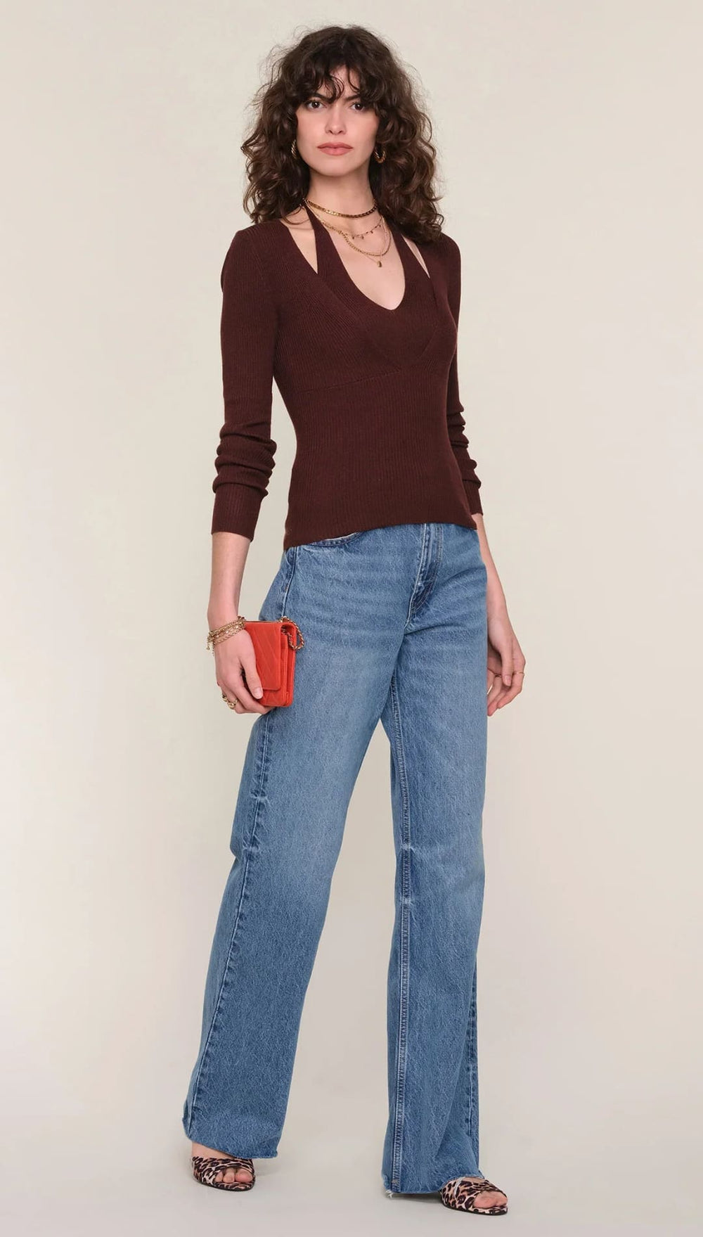 Brown v-neck sweater with cutout detail, light blue denim jeans with pocket design.