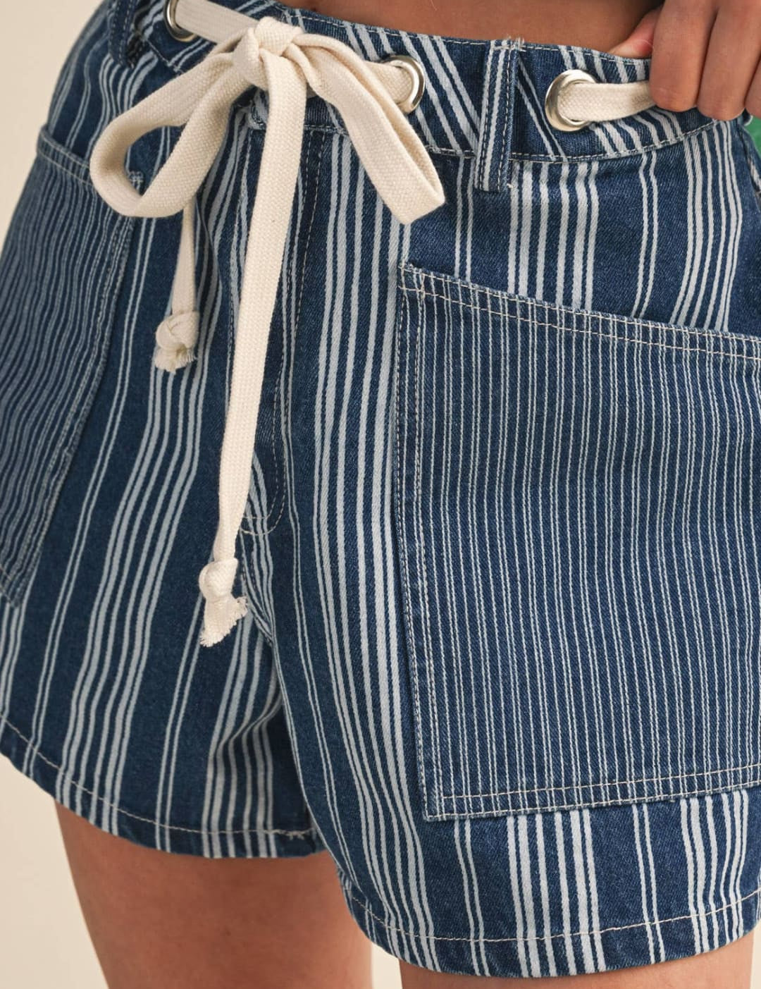 Blue and white vertically striped denim shorts with a cream-colored drawstring waistband.
