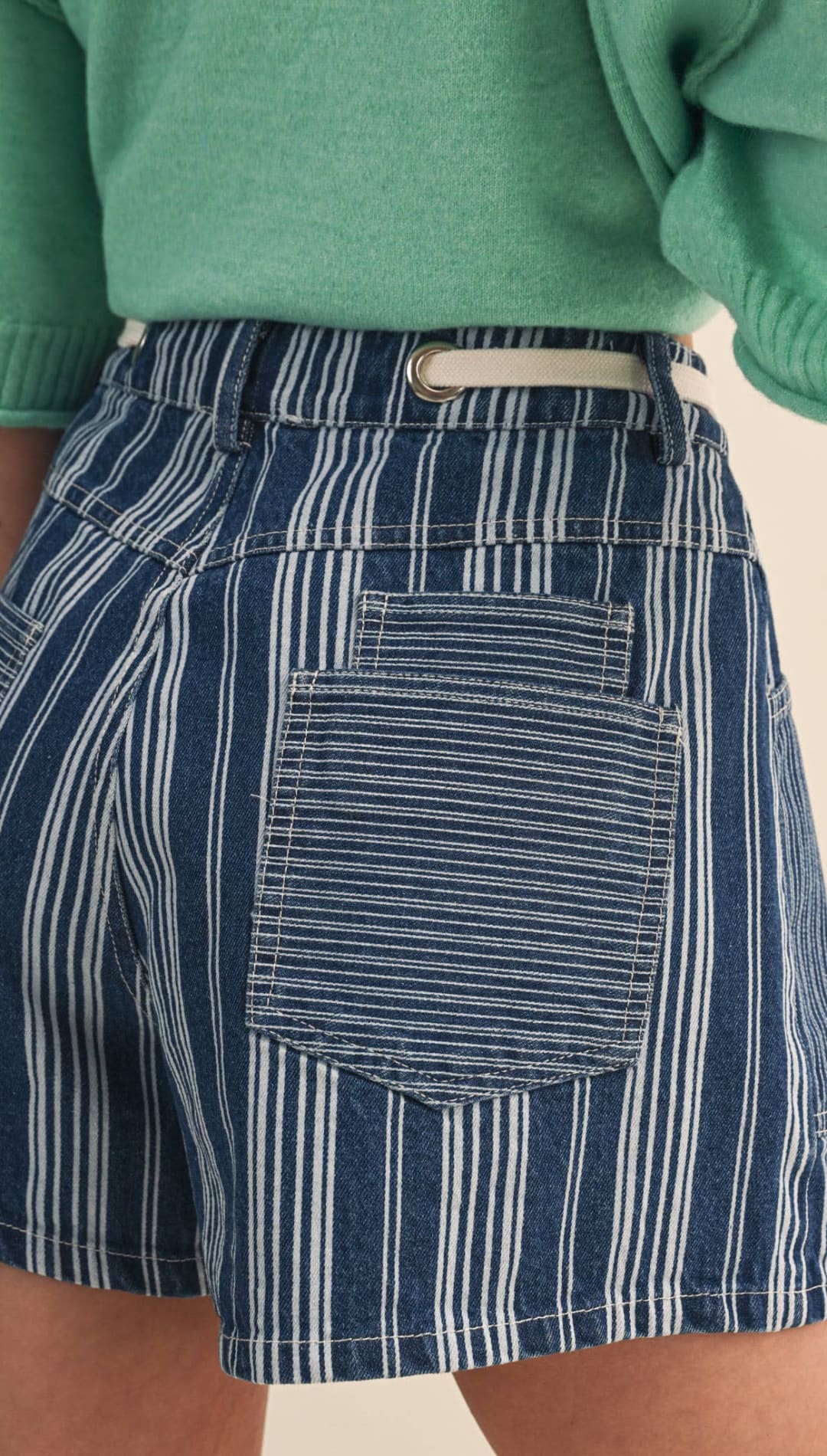 Blue and white vertically striped denim shorts with a light-colored belt loop.
