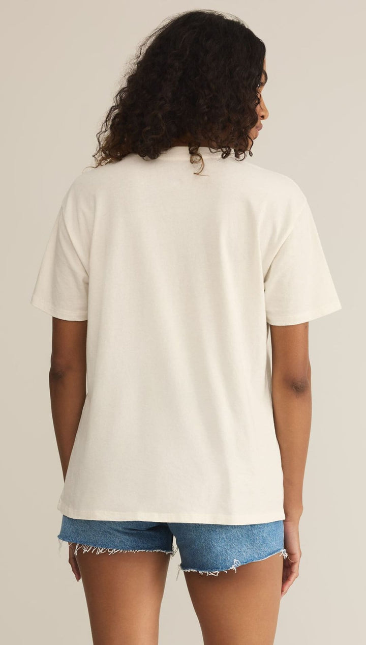 Woman wearing a cream-colored t-shirt and denim shorts.