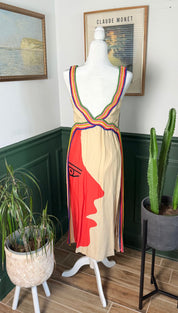 Beige sleeveless dress with a bold red face silhouette and rainbow-striped shoulder straps.