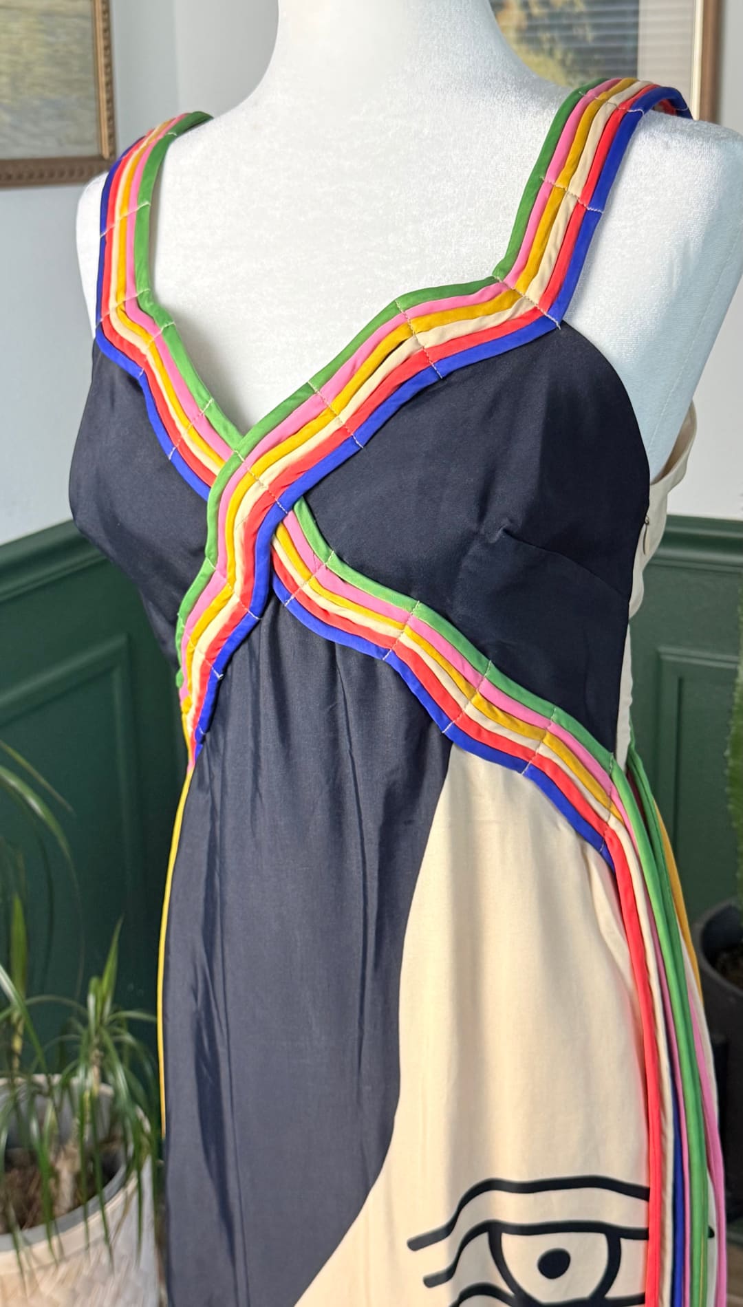 A vibrant, sleeveless dress with a black and cream color-block design featuring bold rainbow-striped trim along the straps and neckline.