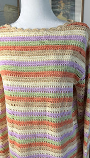 A hand-crocheted sweater with horizontal stripes in soft pastel hues of lavender, mint green, peach, and cream.