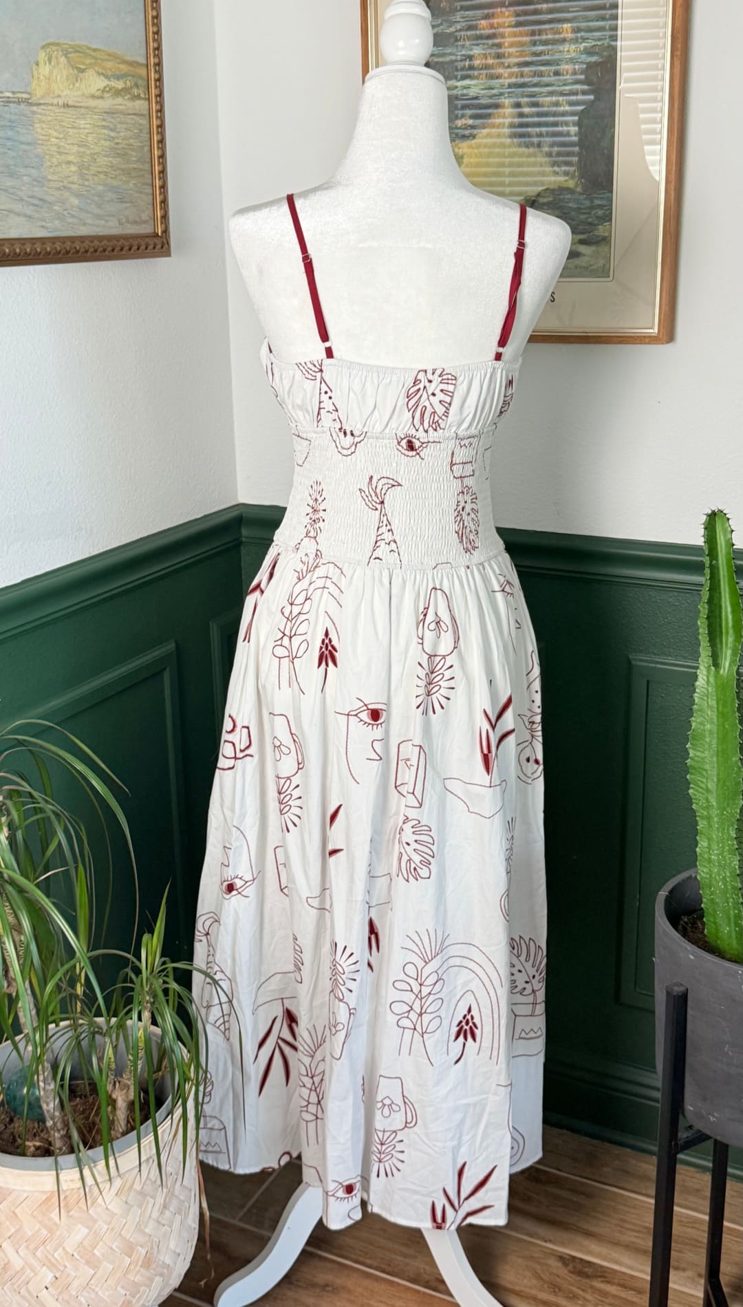 White midi dress with red line-art illustrations of faces and foliage, displayed on a mannequin.