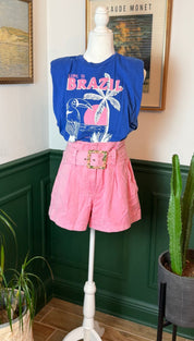Pink pleated shorts with a gold-toned belt buckle.