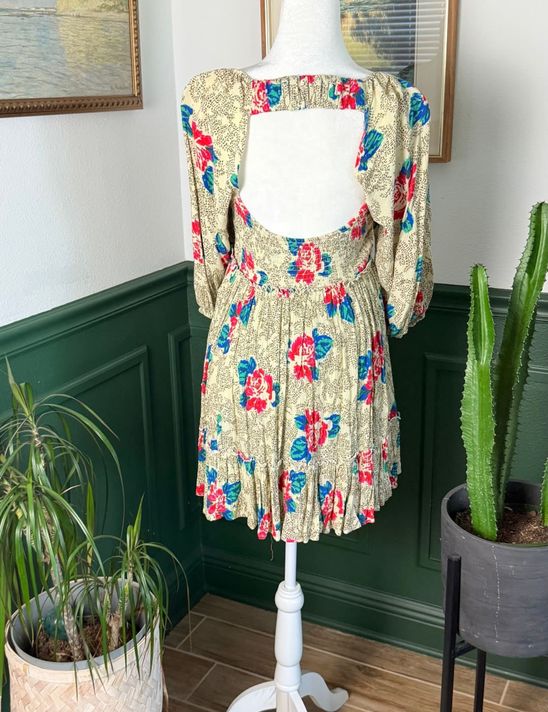 A floral-patterned, short-sleeved dress in a soft beige base with vibrant red and blue blossoms, displayed on a white mannequin.