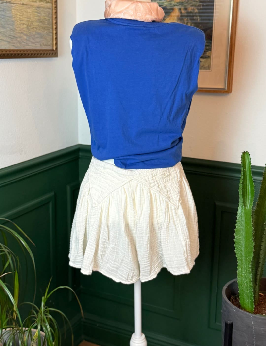 Blue short-sleeved top with a gathered waistline and soft, flowing fabric.
