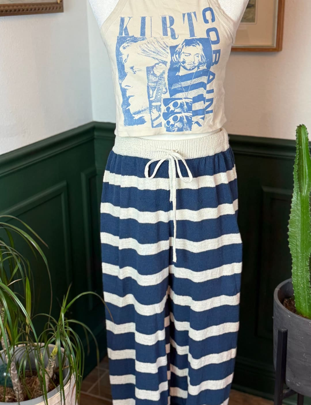 Cream-colored halter top with blue graphic print featuring kirt cobain and striped pattern, paired with navy and white horizontally striped pants.