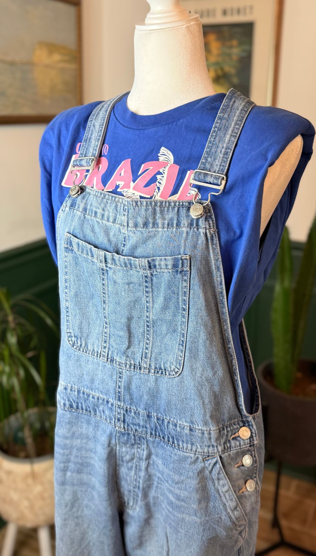 Light-wash denim overalls with adjustable straps and button closures.