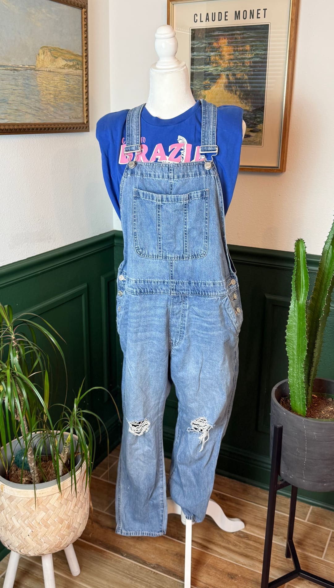 Light-wash denim overalls with distressed patches and button closures.