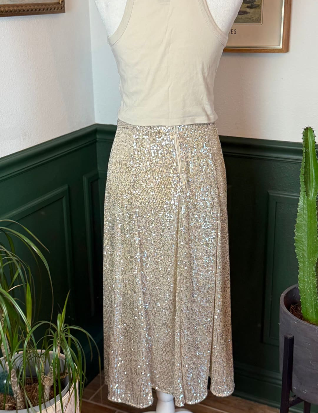 A shimmering gold sequined midi skirt displayed on a mannequin.