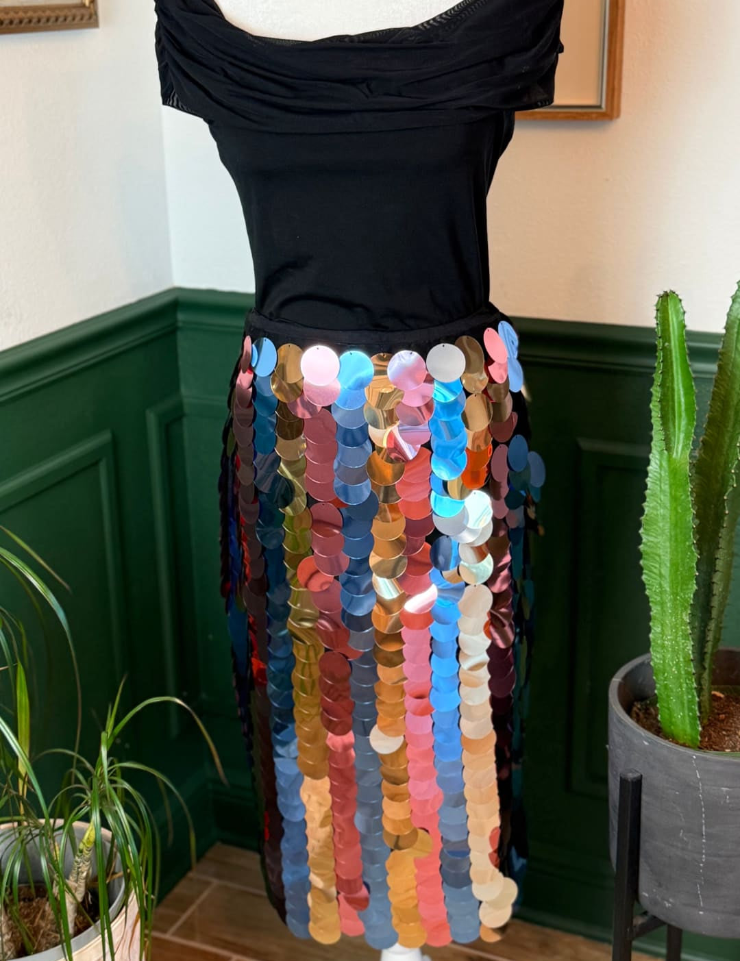 A vibrant, multi-colored sequin skirt with a flowing, off-the-shoulder black top.