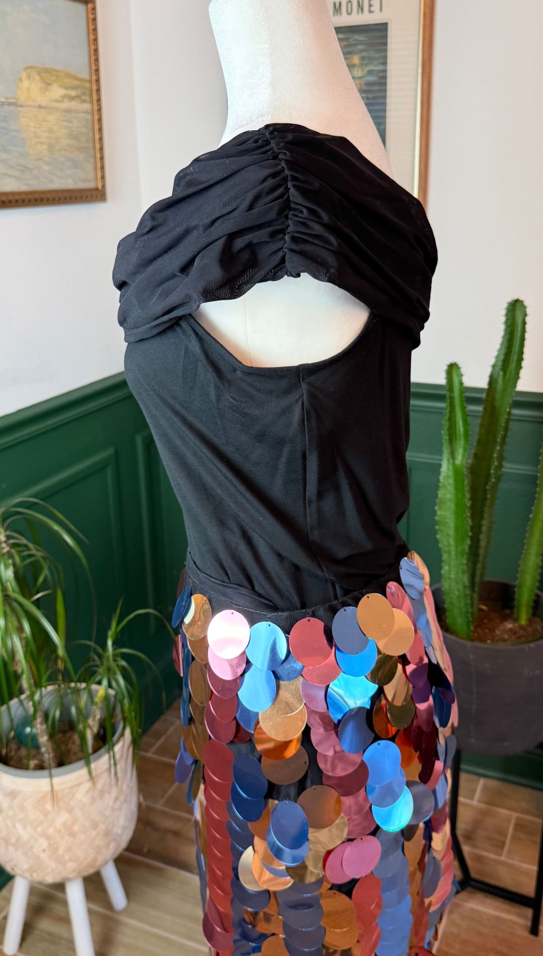 Black off-the-shoulder top with ruched neckline paired with a colorful sequin skirt.