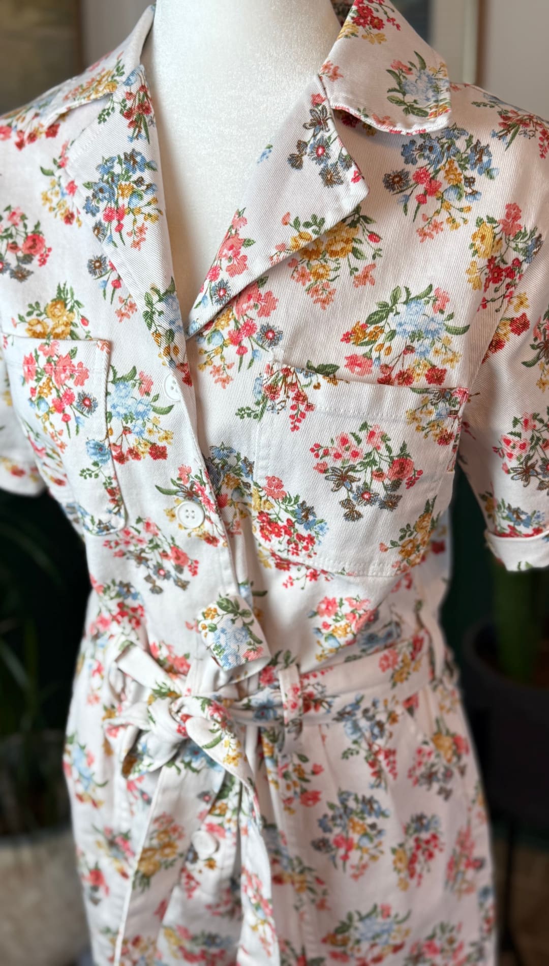 A soft pink floral print dress with short sleeves, a collar, and a tied waistband.