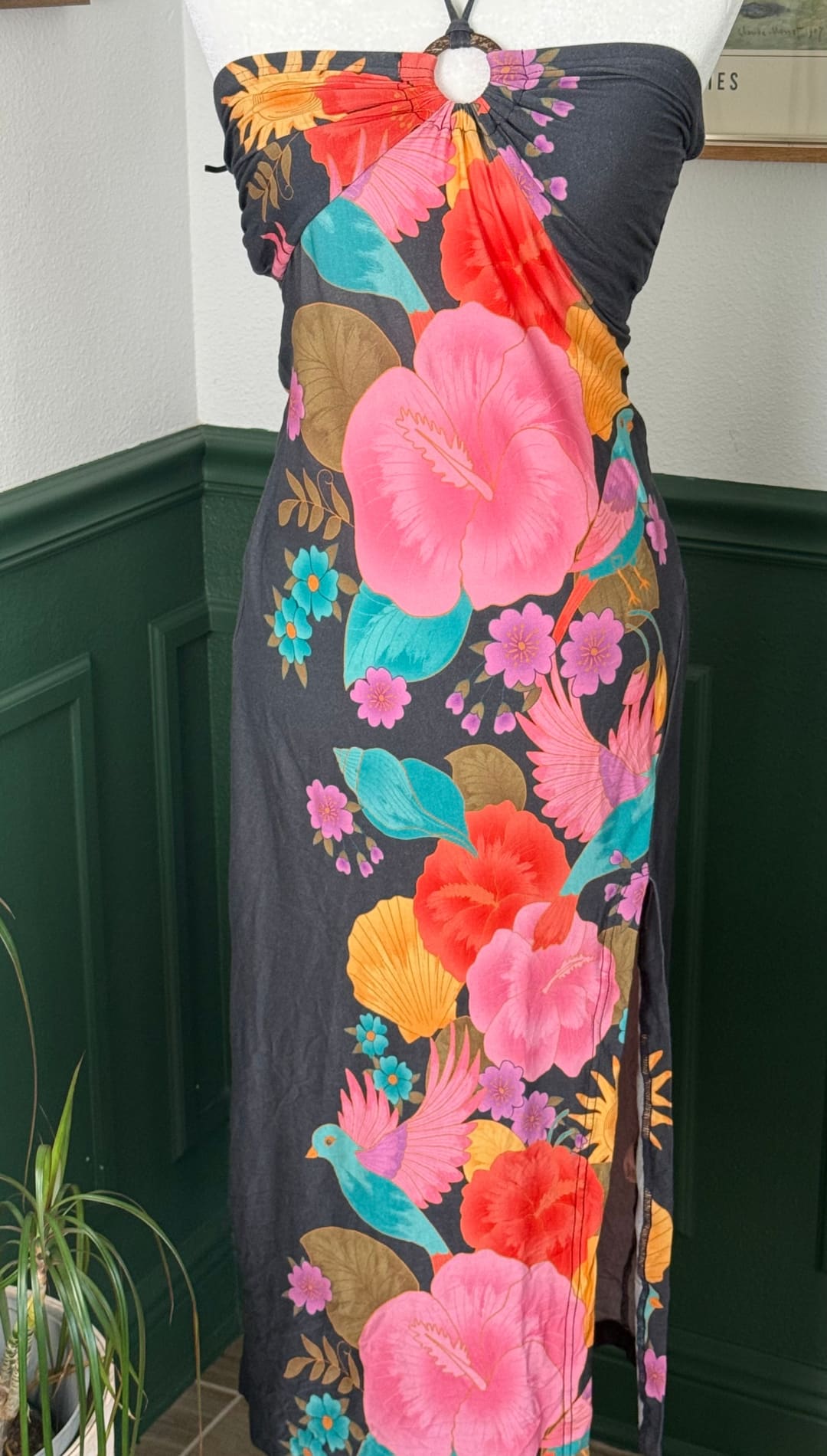 A vibrant floral print strapless dress in dark gray fabric, featuring bold pink hibiscus flowers and colorful tropical birds against a black background.