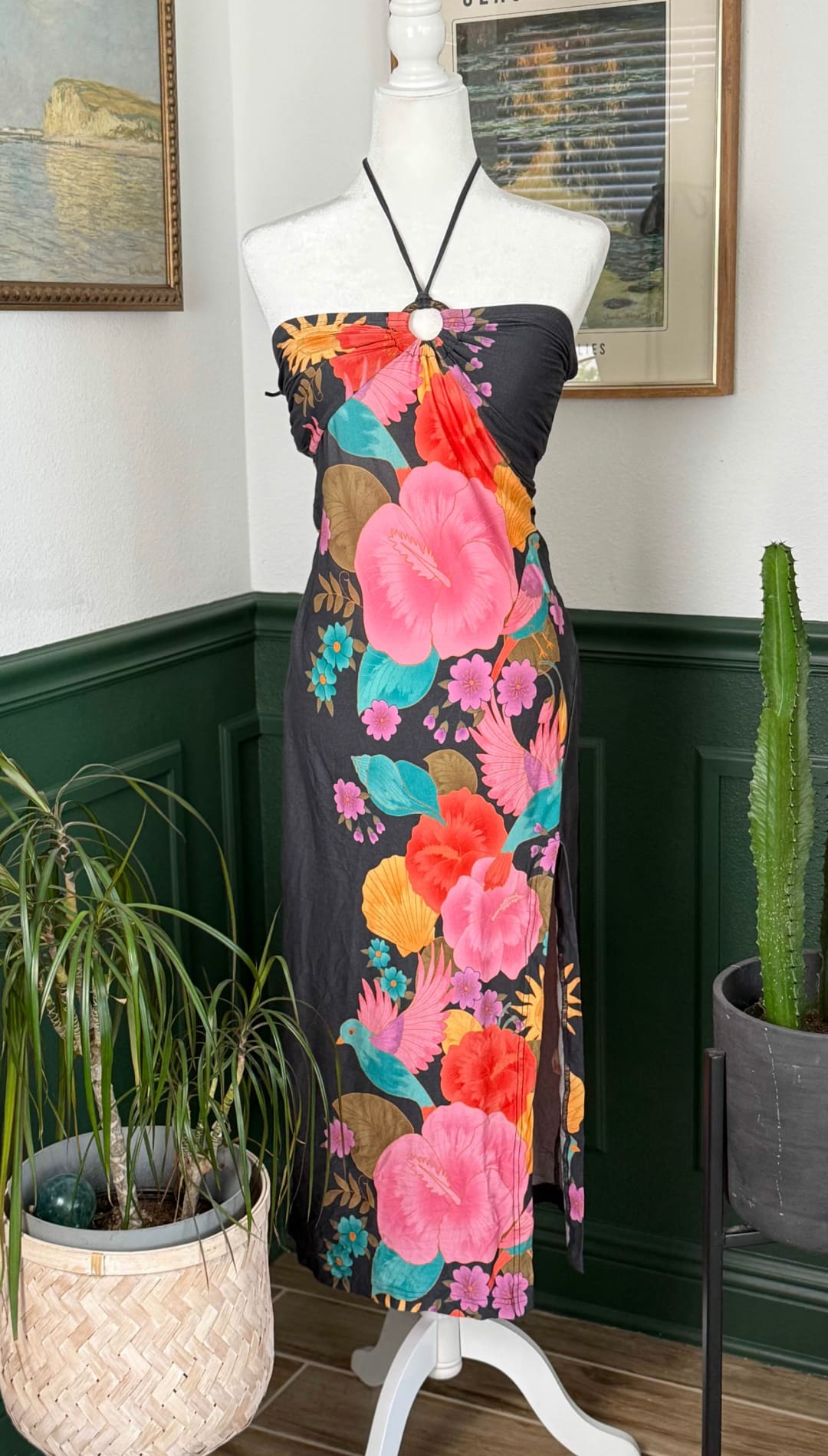 A vibrant floral print halter dress in black fabric, featuring bold pink hibiscus flowers and colorful tropical accents.