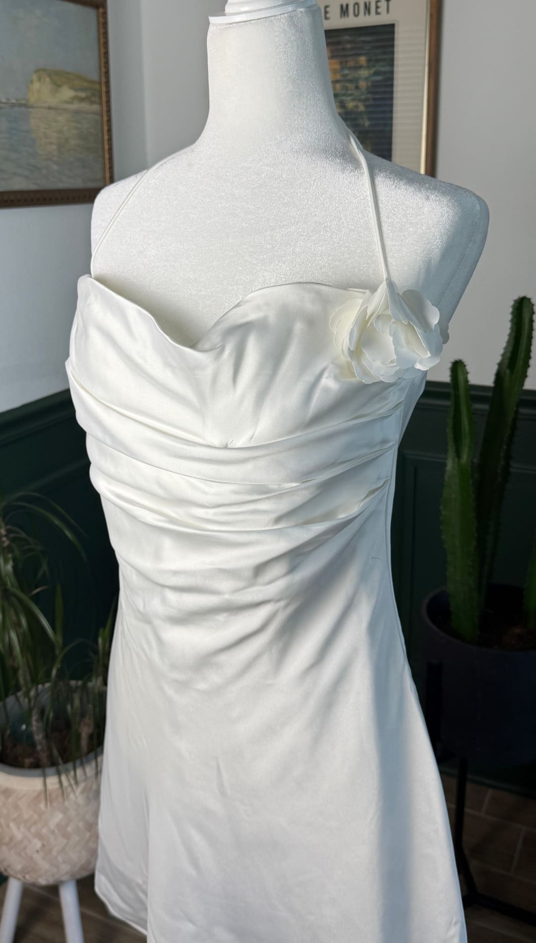 A sleek white satin strapless dress with a draped bodice and delicate ruffled detailing at the neckline.
