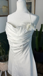 A sleek white satin strapless dress with a draped bodice and delicate ruffled detailing at the neckline.