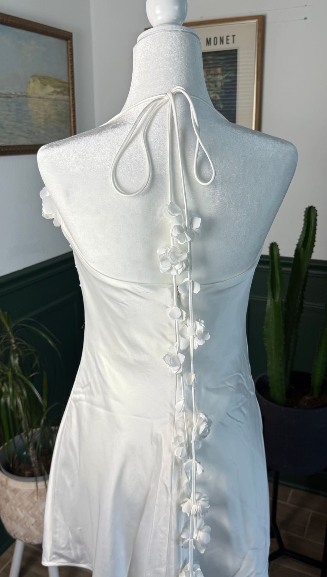 A white satin halter dress with delicate floral appliqués along the back tie.